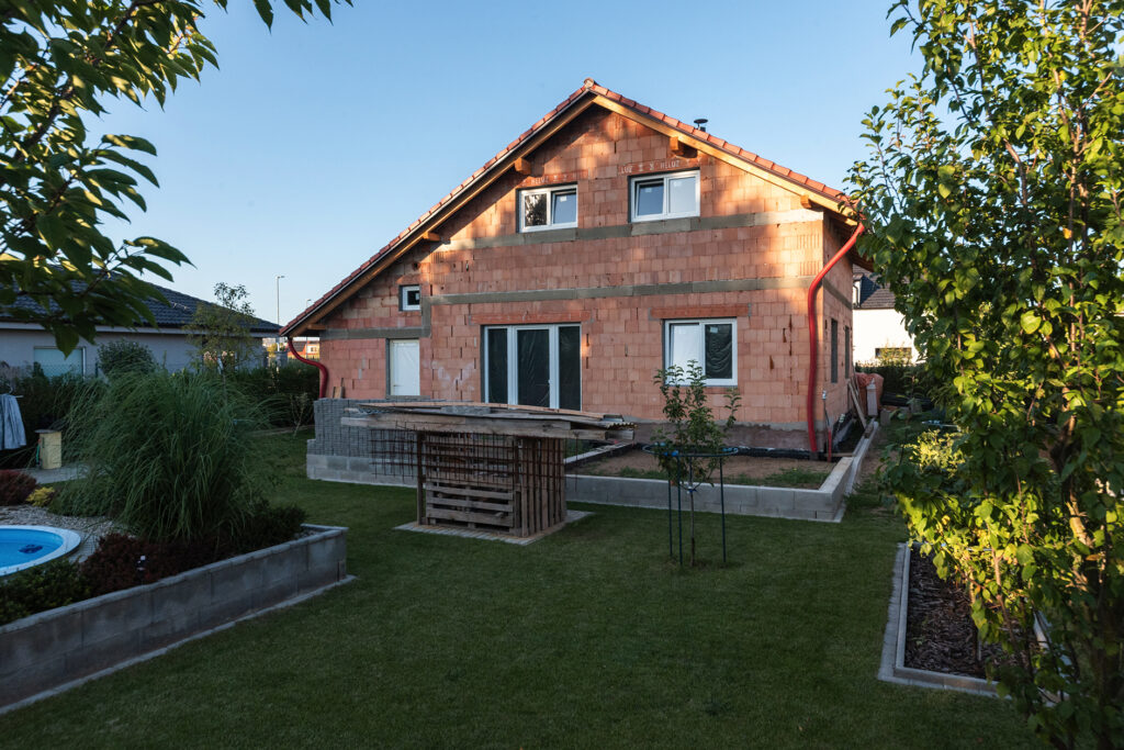 Rodinný dům stavěný svépomocí z cihel HELUZ, pohled na zadní část domu se zahradou.