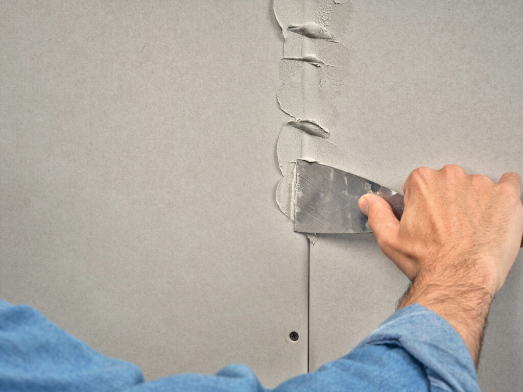 Tmelění spáry mezi sádrokartonovými deskami pomocí nerezové špachtle