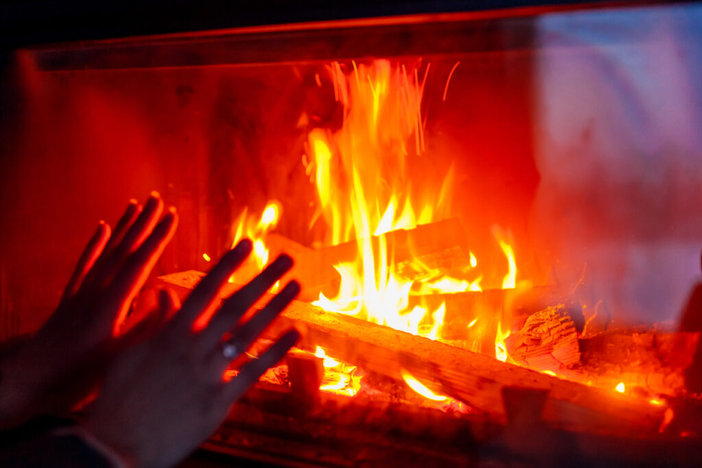 ruce u hořícího ohně v krbu